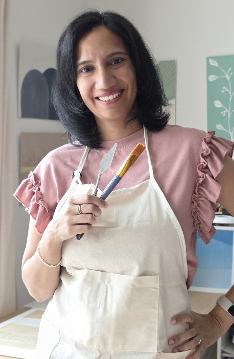 Sim in her studio, holding a palette knife and brush